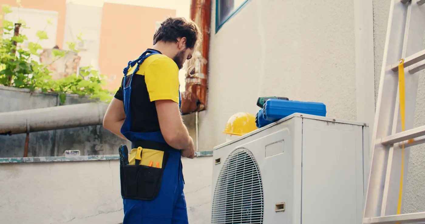 professional technician performing maintenance or repair on an outdoor HVAC air conditioning unit