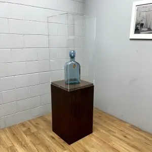 Blue glass bottle on a natural wood raised-top pedestal