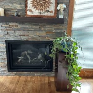 Espresso-finish rectangle pedestal beside a stone fireplace and plant