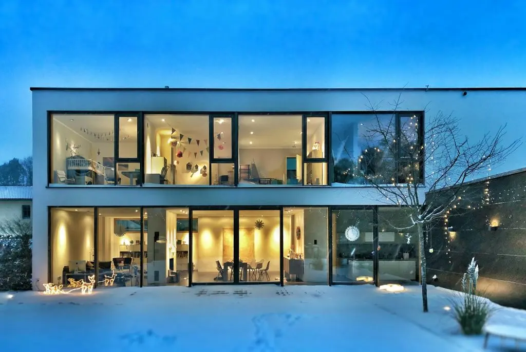 Modern home lit warmly on a snowy evening