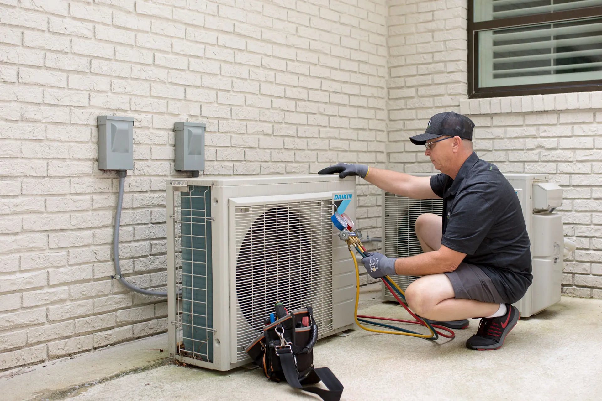 Autumn Air technician checking refrigerant pressure on a Daikin outdoor unit