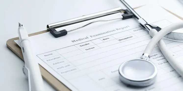 A medical examination report clipboard with a white stethoscope and pen, detailing essential documentation for personal injury claims.
