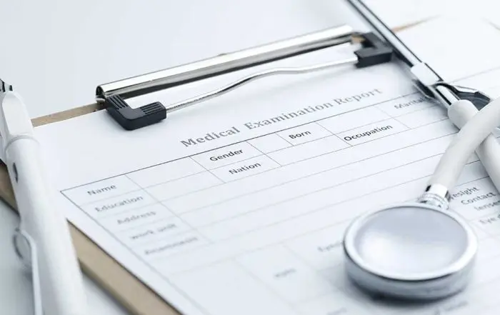 A medical examination report clipboard with a white stethoscope and pen, detailing essential documentation for personal injury claims.
