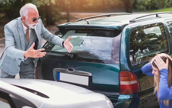 An angry driver gesturing at a stressed woman after a car collision, illustrating steps following an uninsured driver accident.