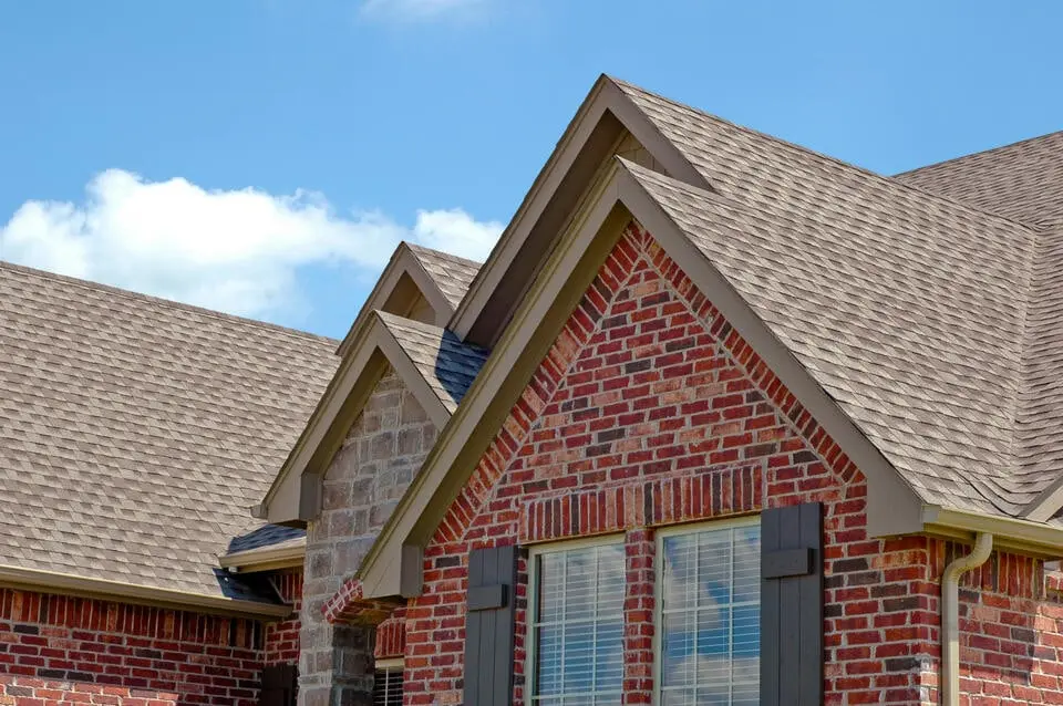 brick sided house with new gray shingle roof