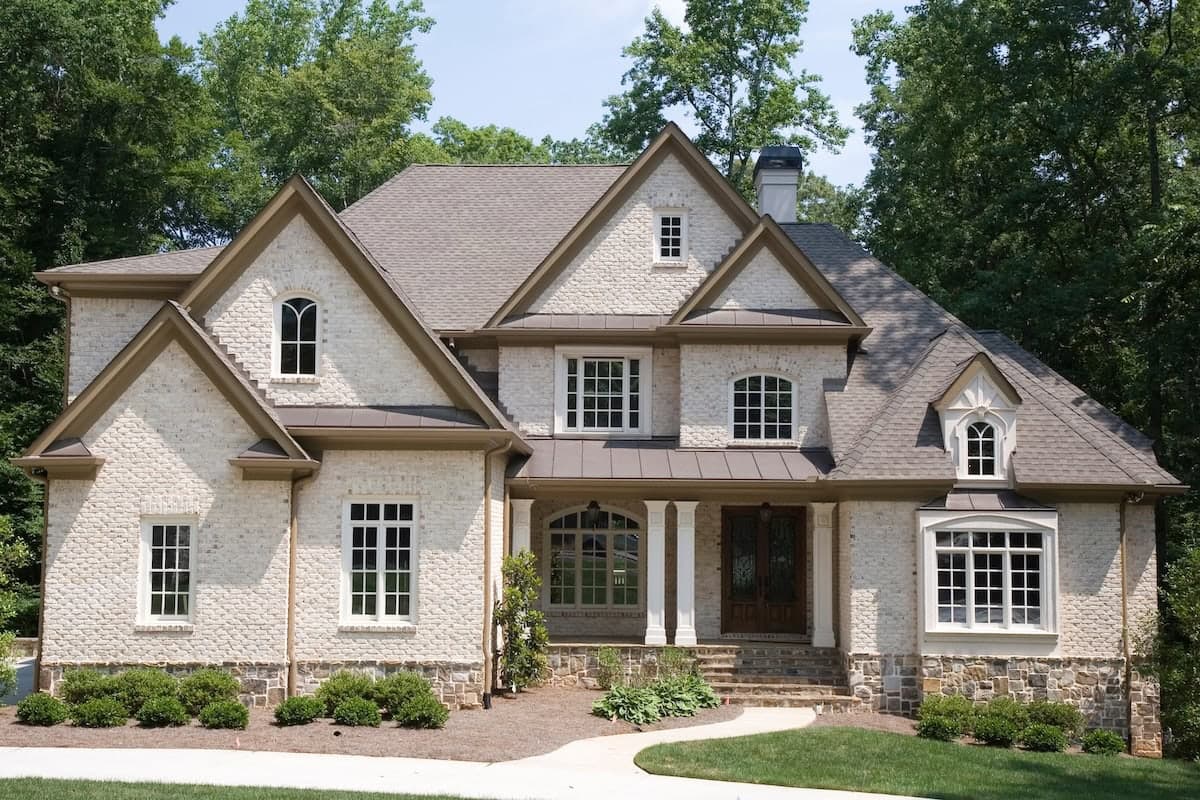 A tan brick house with many gables and roof lines