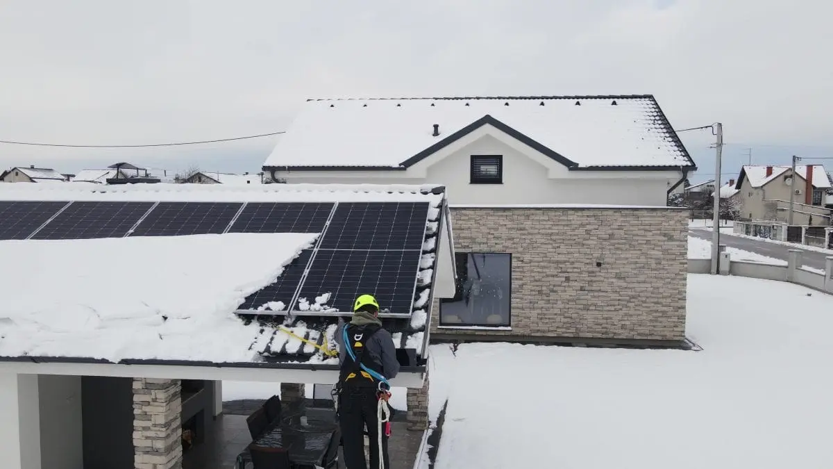 worker removing snow on top of roof