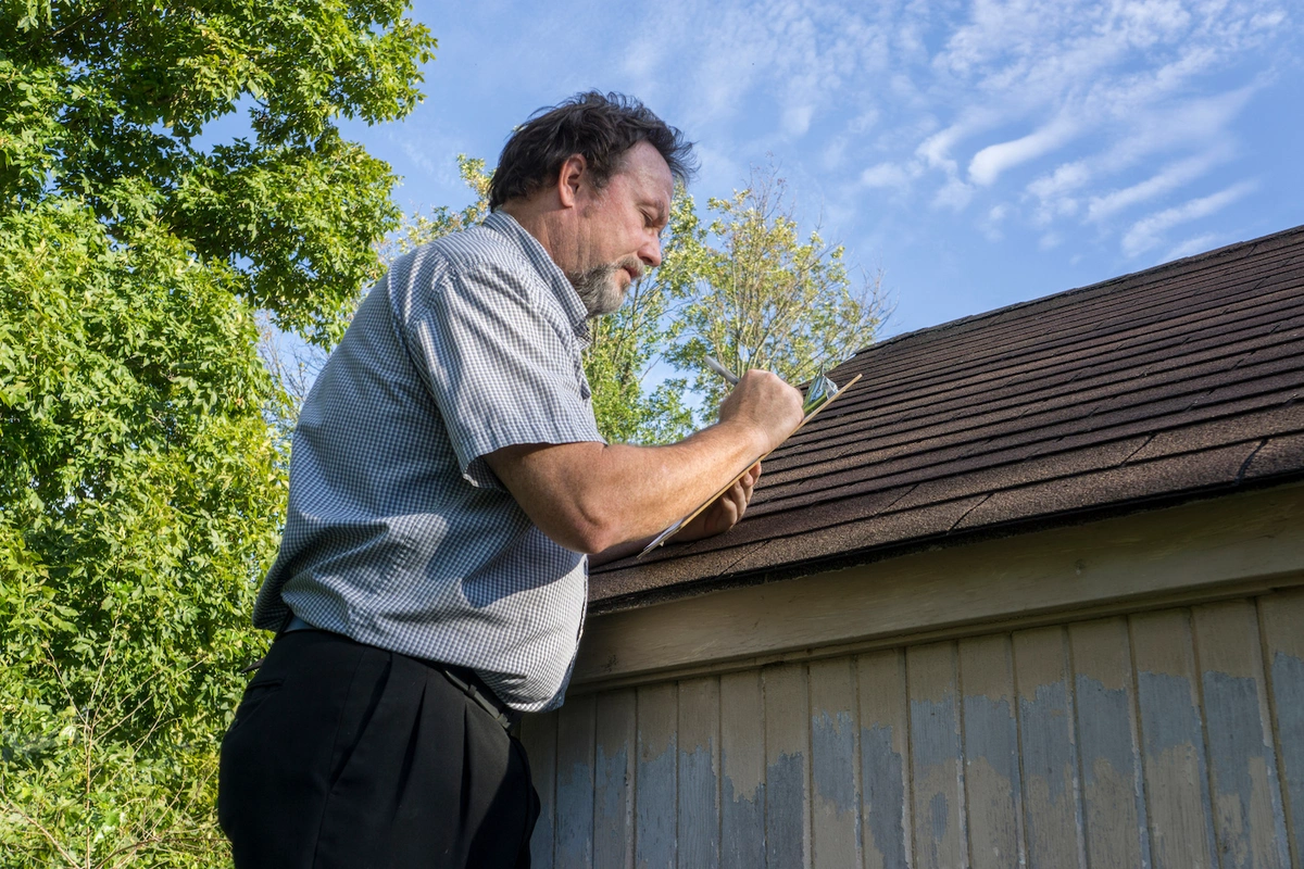 roofing contractor with clip board shows how to inspect a roof for damages