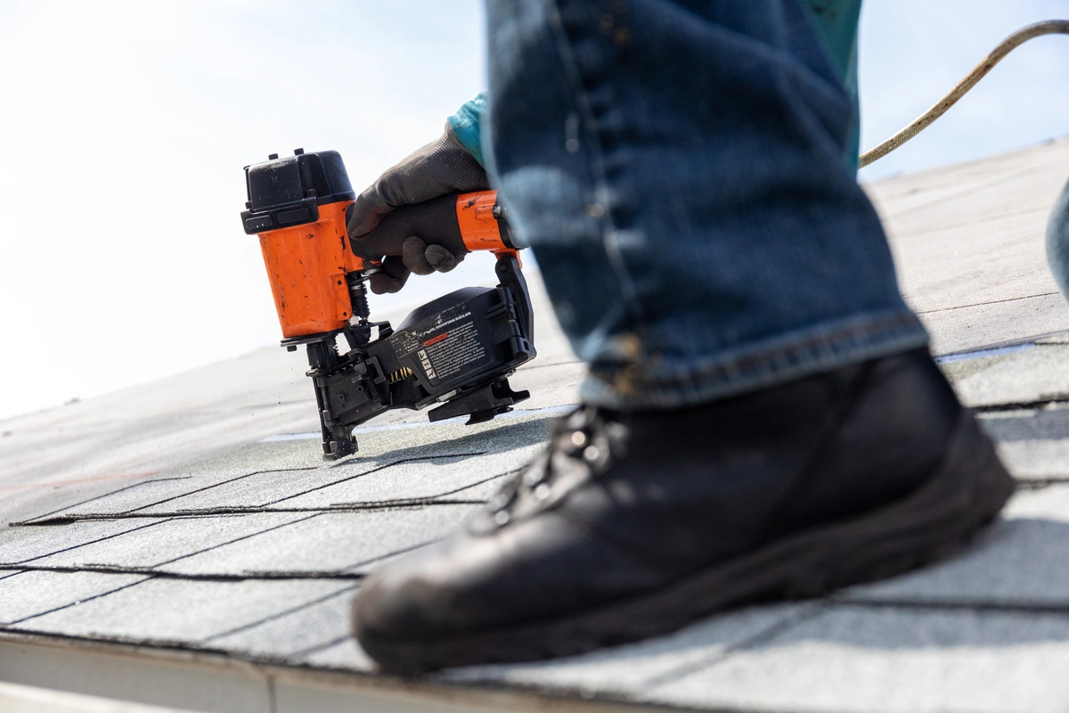 a foot and a nail gun. roof installation process