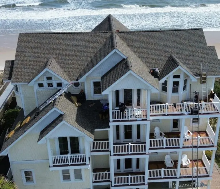 large house with a newly installed shingle roof, next to a beach