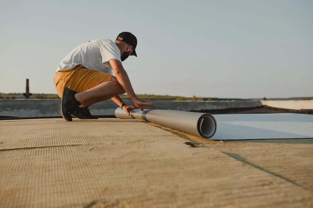 pvc flat roof Worker applies pvc membrane roller on roof very carefully