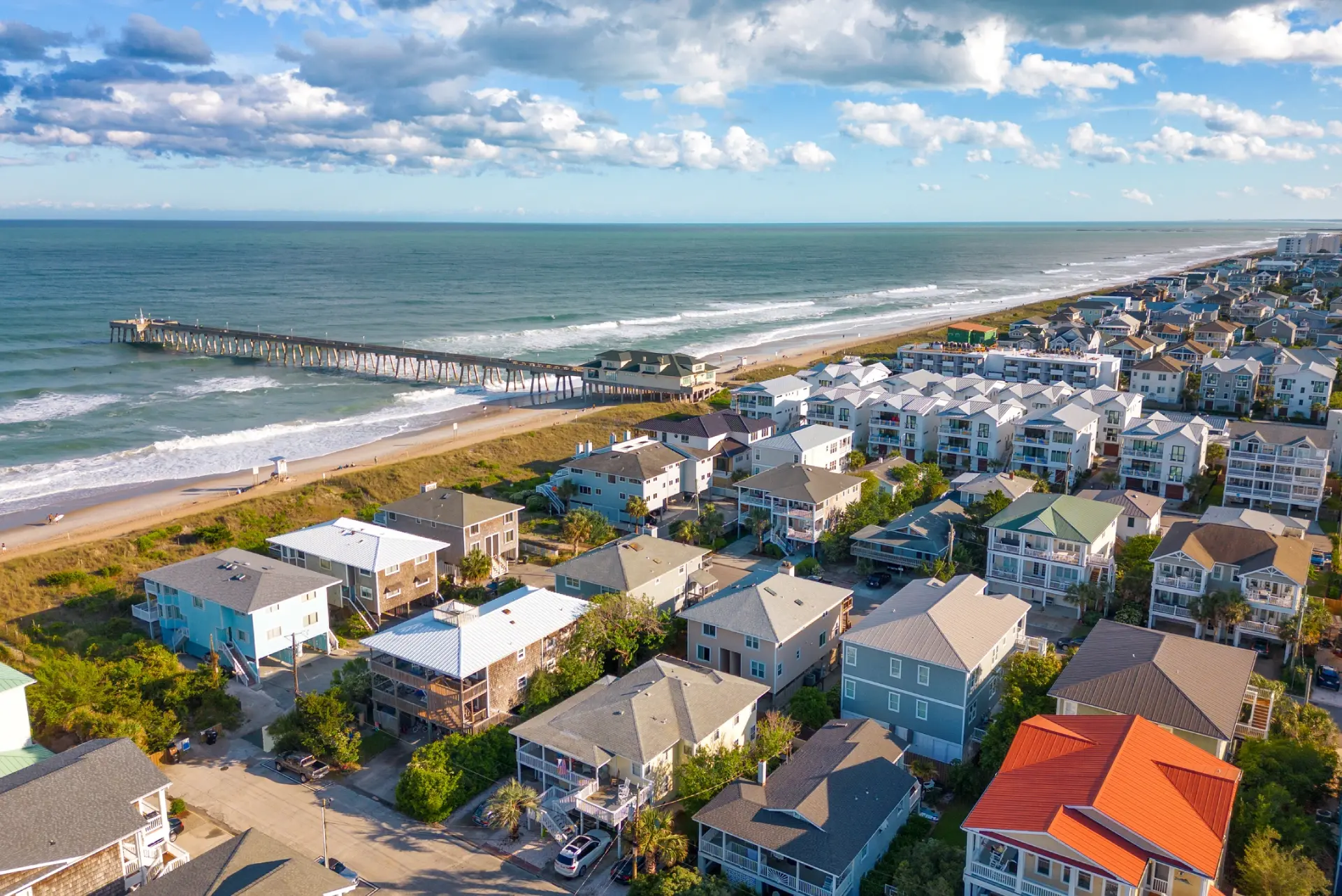 Aerial view of Wrightsville Beach NC with oceanfront homes, fishing pier, and sandy beach