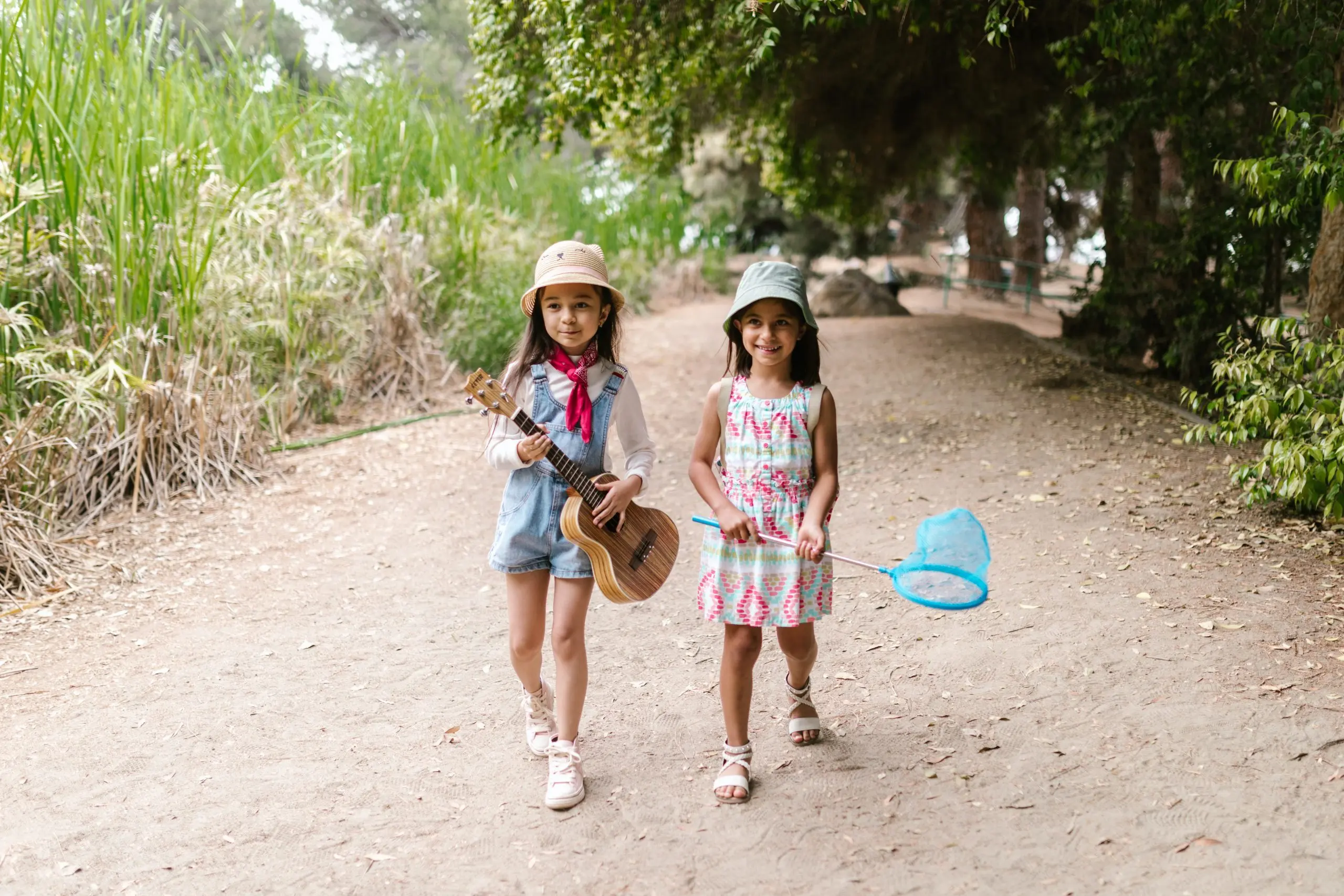Two girls walking on a dirt road carrying butterfly nets
