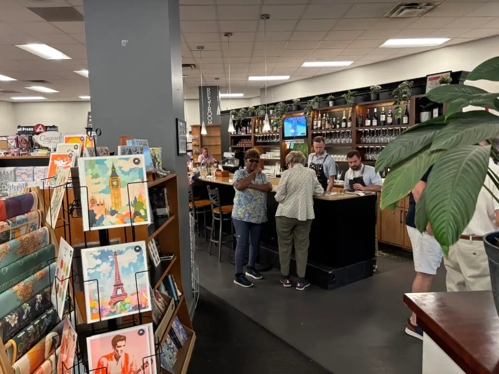 Two ladies chatting in front of a black bar with two servers behind the bar at Novel bookstore