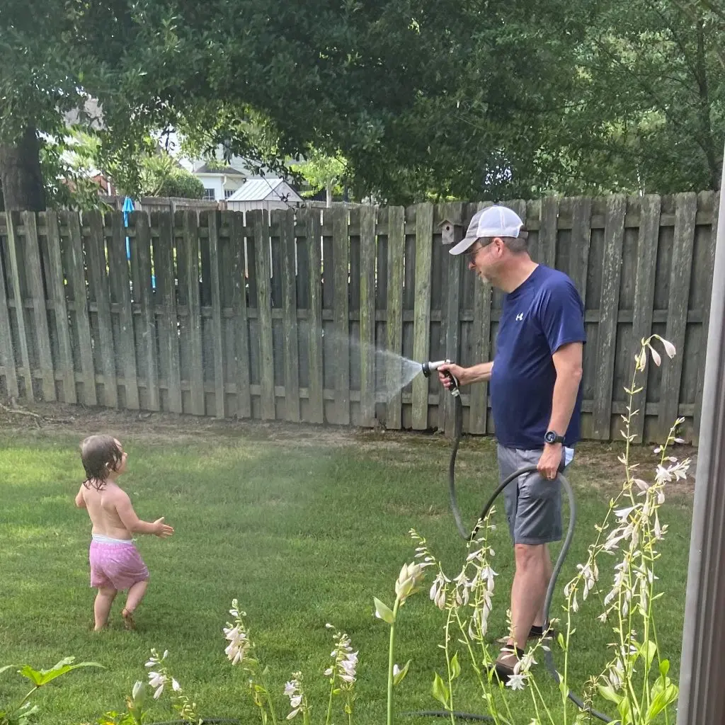 dad and baby playing in the hose