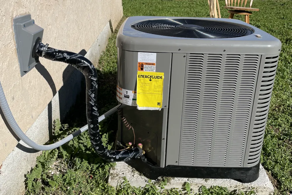 Picture of a newly installed air conditioning unit next to an exterior wall.