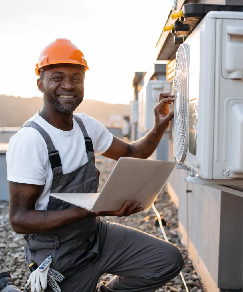 HVAC technician repairing commercial HVAC systems with laptop in hands.