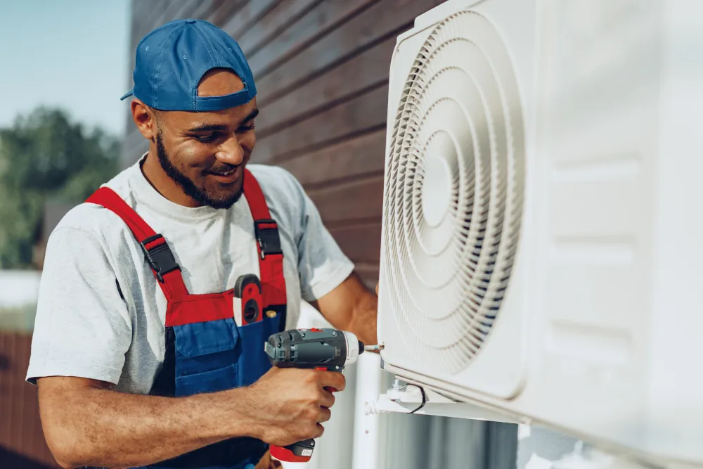 HVAC technician installing air conditioner on an exterior wall.