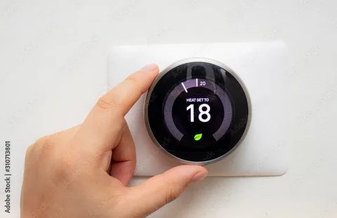 Hand adjusting smart thermostat to heating mode during fall transition