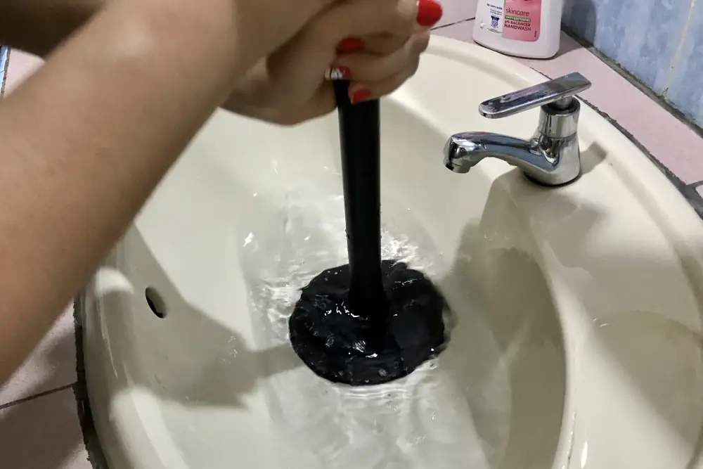 Plumbing mishaps Precision Plumbing, Calgary - Personal using a plunger to unclog a sink