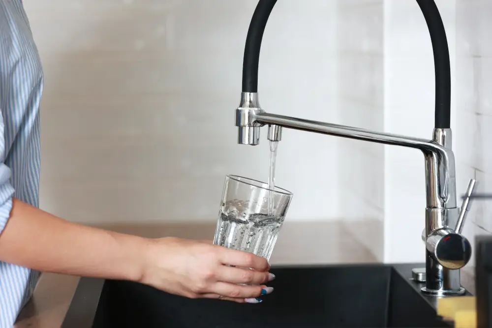 Backflow Prevention In Calgary, Keeping Your Water Crystal Clear - Person filling up a glass with tap water.