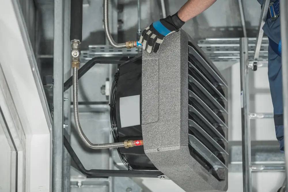 Garage heaters comfort in Calgary, AB - Technician Servicing Warehouse Heating Unit Attached to Building Wall