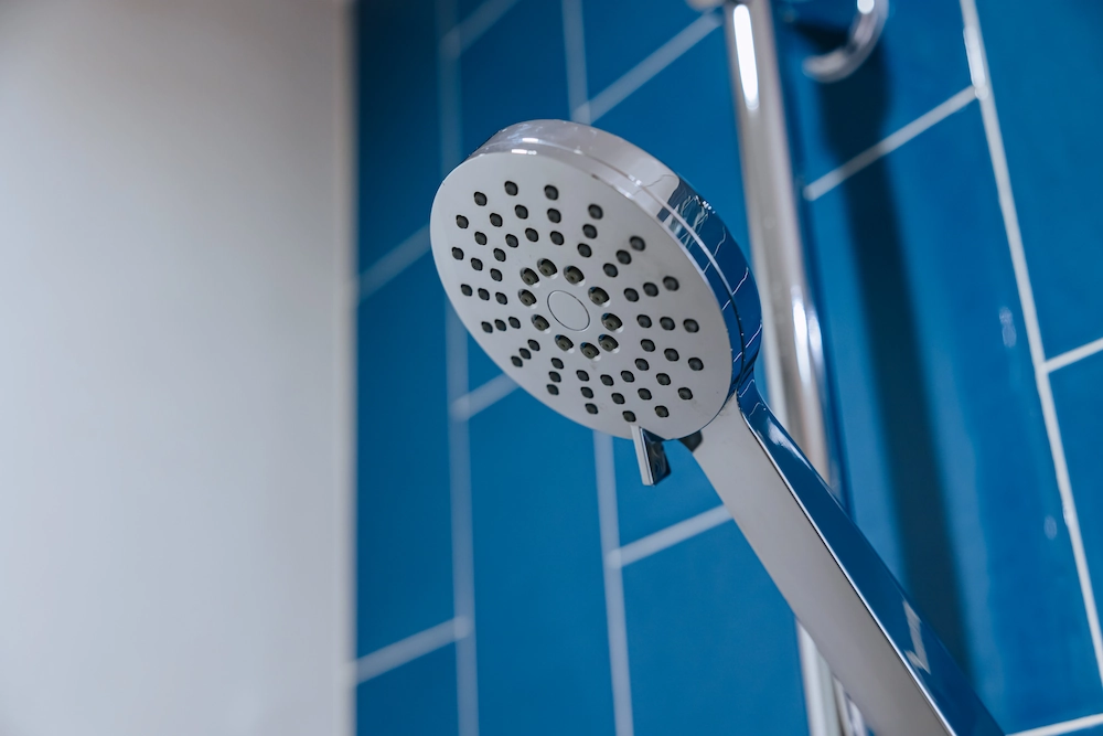 Closeup Clean New Chrome Shiny Dry Shower Head In Bathroom Blue Wall Background