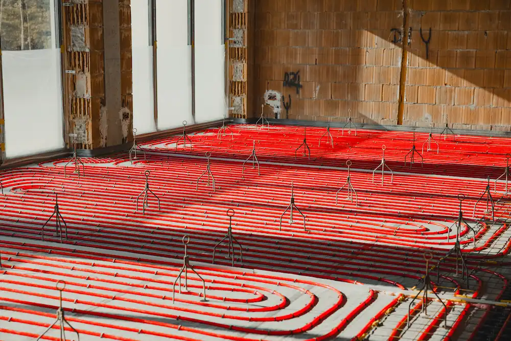 Installing underfloor heating system in new building with red pipes