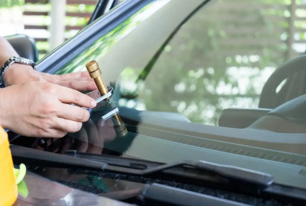 Glazier using tools repair to fix crack windshield