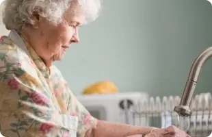 Elderly lady washing hands at sink
