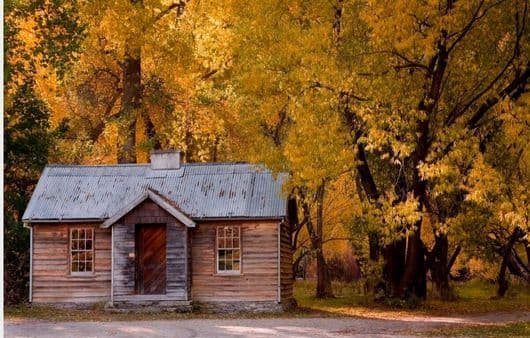 Historic police hut in Arrowtown among autumn trees