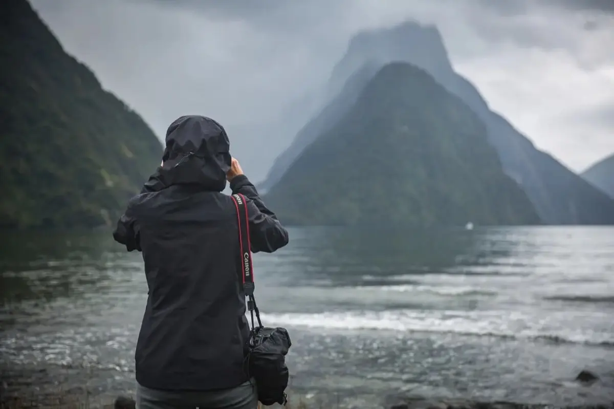 Visitor photographing Mitre Peak at Milford Sound on a misty day