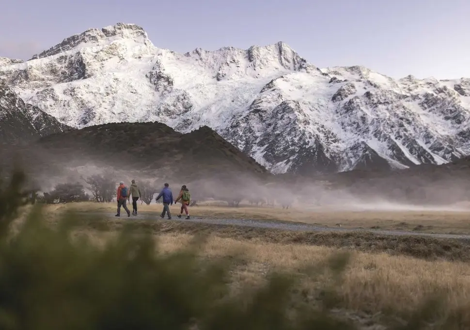Walkers on the Hooker Valley Track below snow-covered mountains in Aoraki Mount Cook National Park