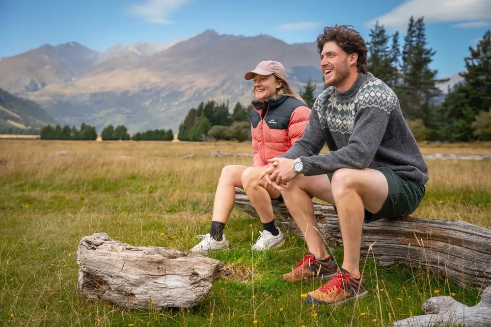 Two guests sitting on a log on the tussock flats near Diamond Lake