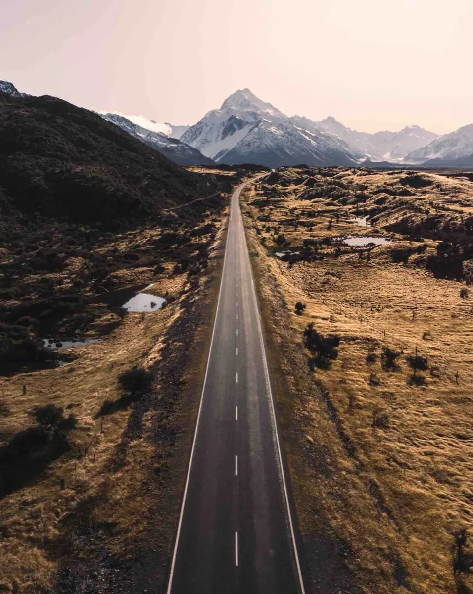 The straight road to Aoraki Mount Cook through golden tussock
