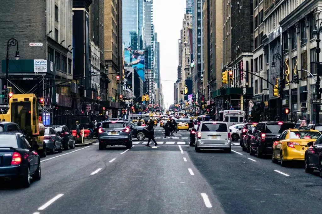 Dense multi-lane traffic with taxis, cars, and transit buses passing beneath red signals downtown.