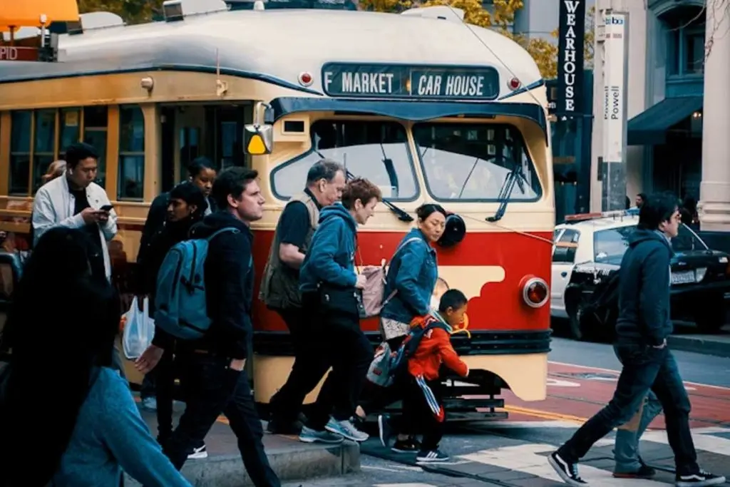 Vintage San Francisco streetcar stopped at a crosswalk as pedestrians cross in front of it.