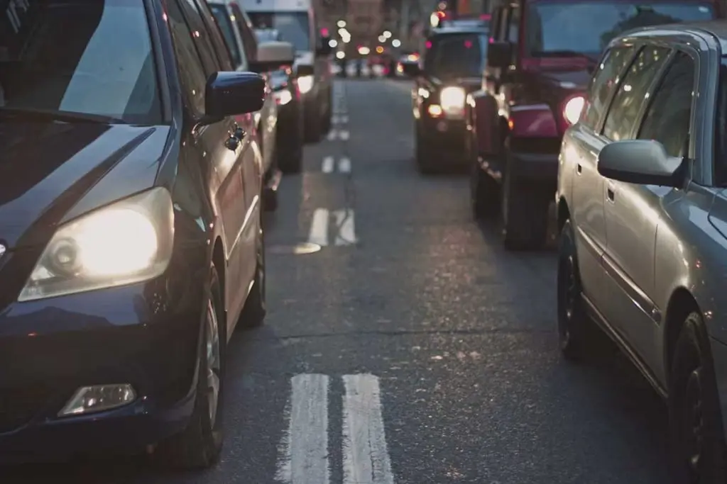 Two lanes of commuter traffic queued bumper-to-bumper with headlights illuminated.