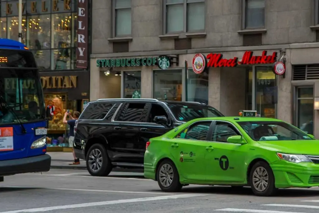 axi and transit bus sharing a downtown intersection, reflecting the mix of rideshare and transit options TDM programs support.