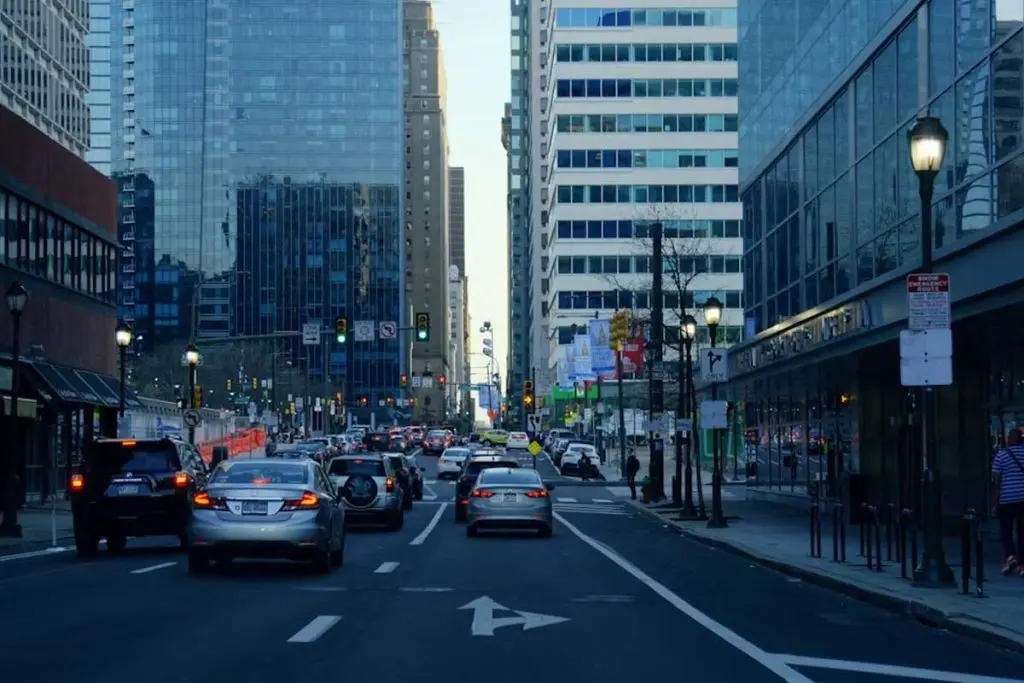 Traffic moving through a high-rise city canyon beneath cool blue streetlights.