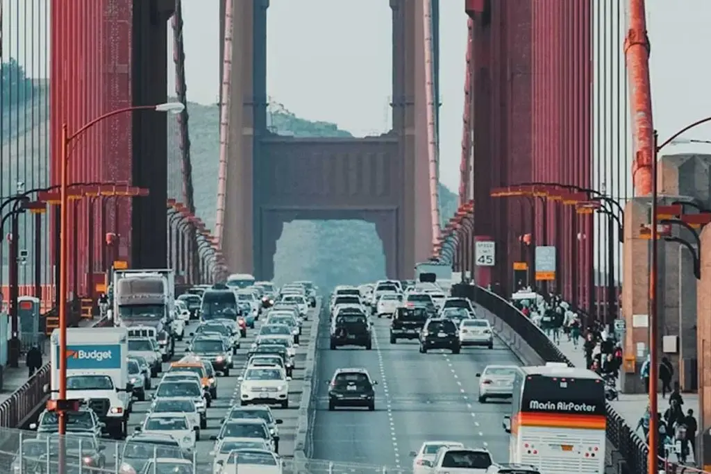 Vehicles and a Marin AirPorter bus crossing the Golden Gate Bridge beneath its orange suspension towers.