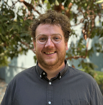 Jack Smith, ALTRANS TMA team member, smiling in a gray button-down shirt against a leafy green background.