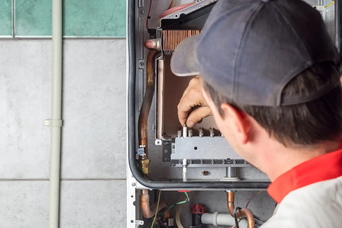 The master sets up a gas boiler, which weighs on the wall. The front dashboard is open. The removal and installation of gas nozzles for gas supply.