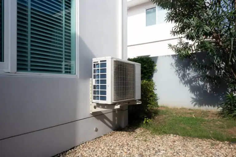 Outdoor air conditioning unit on side of residential house, system mounted on exterior wall