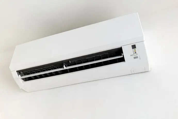 Wall-mounted split air conditioner unit on white wall, indoor climate control.