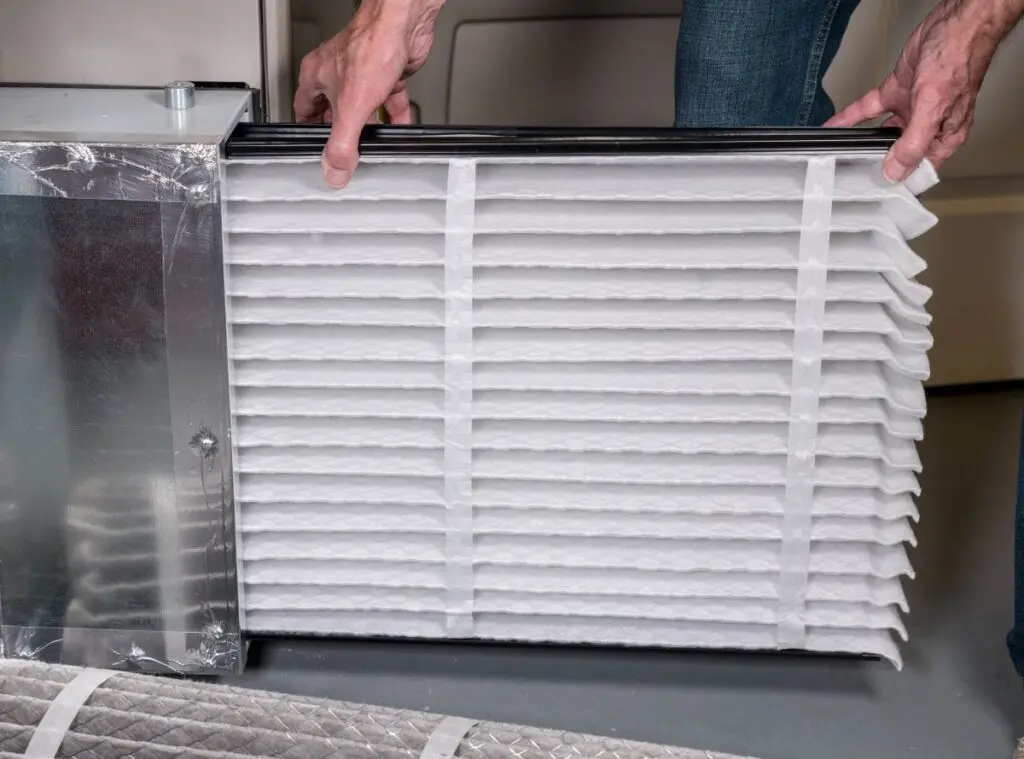 man inserting a new air filter in HVAC furnace