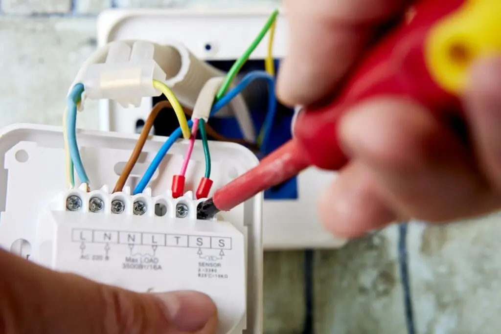 thermostat wiring two man hands fixing thermostat with red screwdriver