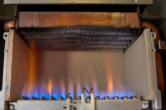 Gas burning in a heating appliance. A stainless steel burner heats a copper heat exchanger. Heat Exchanger Replacement.