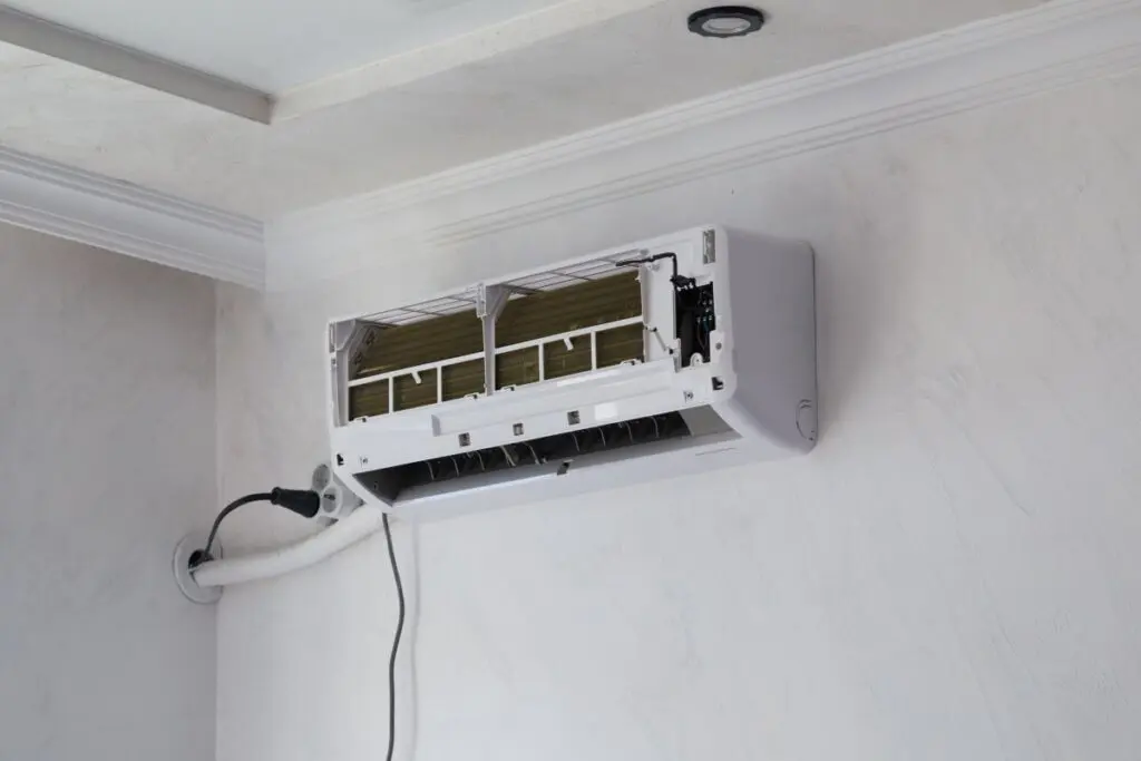 Wall-mounted air conditioner unit opened for repair and filter cleaning