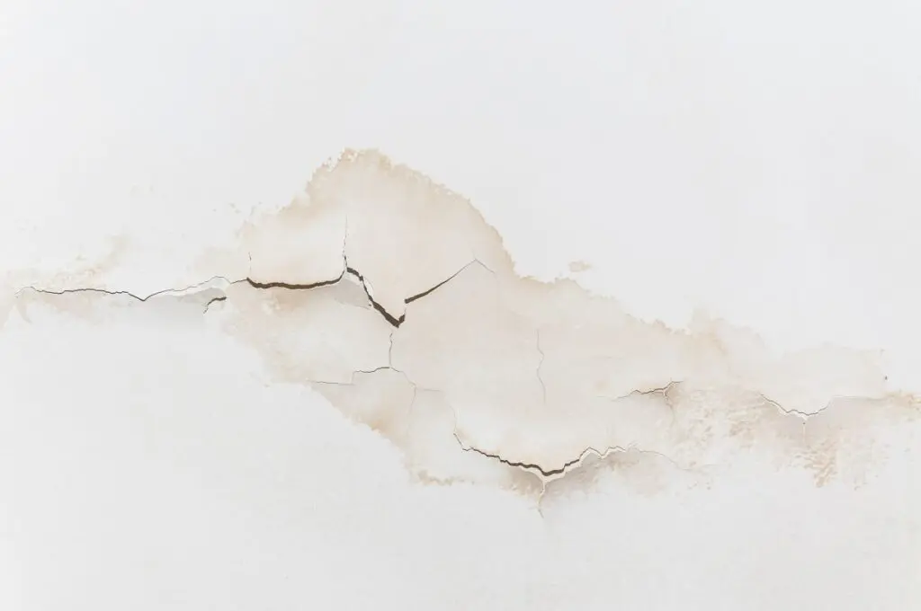Big wet spots and cracks on the ceiling of the domestic house room after heavy rain and lot of water